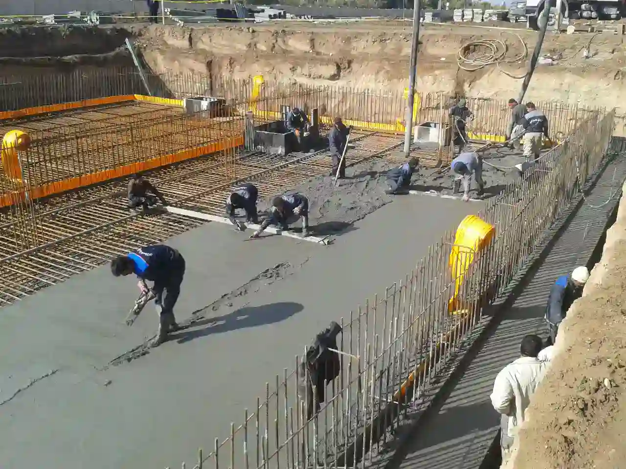 Workers leveling fresh concrete over a large slab at Zarnam wastewater treatment site